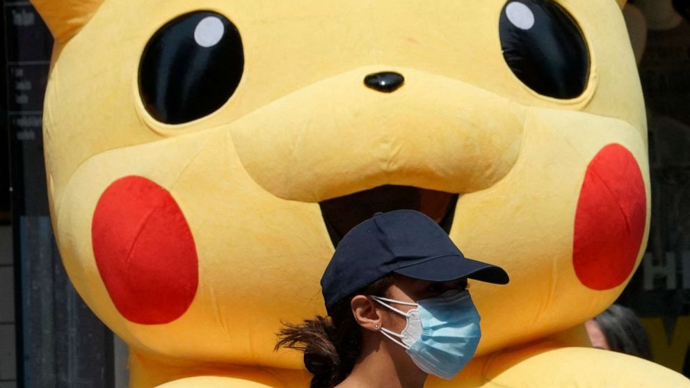 PHOTO: A young person wearing a mask for COVID-19 protection walks past a Pikachu mascot at Times Square on July 22, 2021 in New York. 
