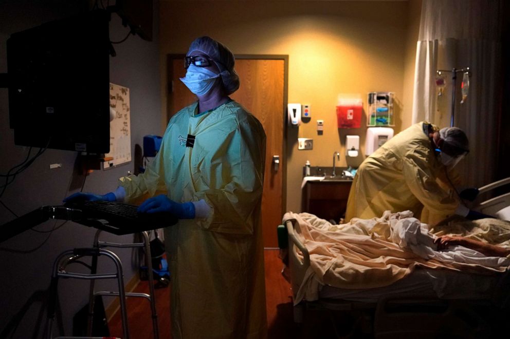 PHOTO: Nurse Shelly Girardin, left, is illuminated by the glow of a computer monitor as Dr. Shane Wilson examines COVID-19 patient Neva Azinger inside Scotland County Hospital, Nov. 24, 2020, in Memphis, Mo.