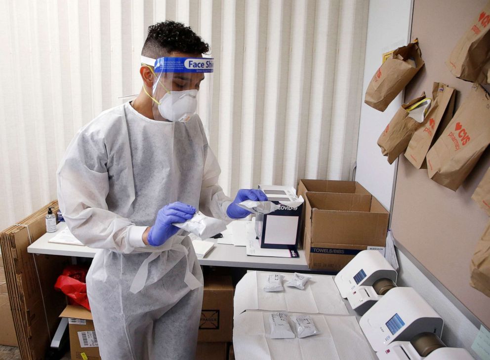 PHOTO: Berto Cortez, a CVS pharmacy technician, shows how COVID-19 tests are processed in a testing area set up by CVS at St. Vincent de Paul medical clinic, June 15, 2020, in Phoenix.