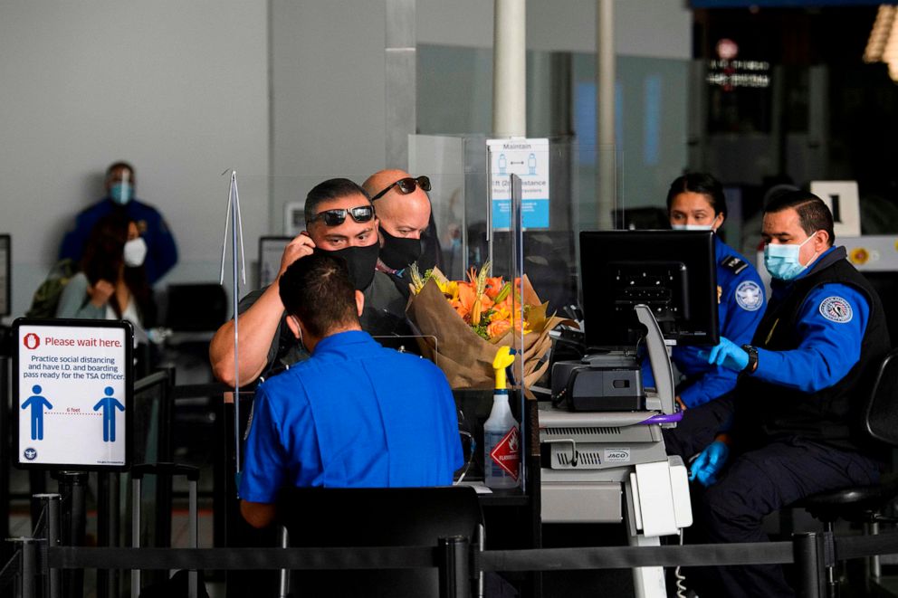PHOTO: A passenger removes their face mask for an identification check at a Transportation Security Administration (TSA) checkpoint at Los Angeles International Airport in Los Angeles,  Nov. 18, 2020.