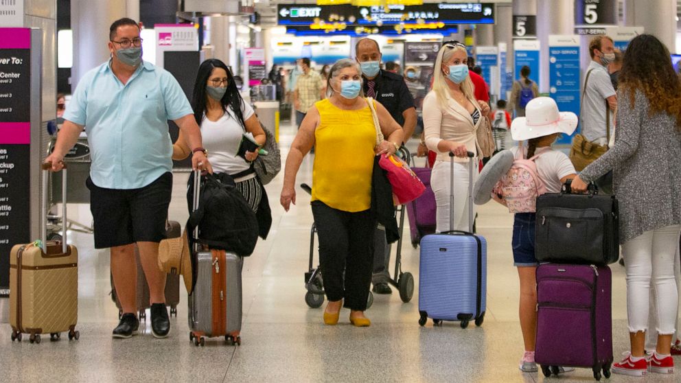 PHOTO: Travelers wearing protective face masks walk through Concourse D at the Miami International Airport, Nov. 22, 2020.