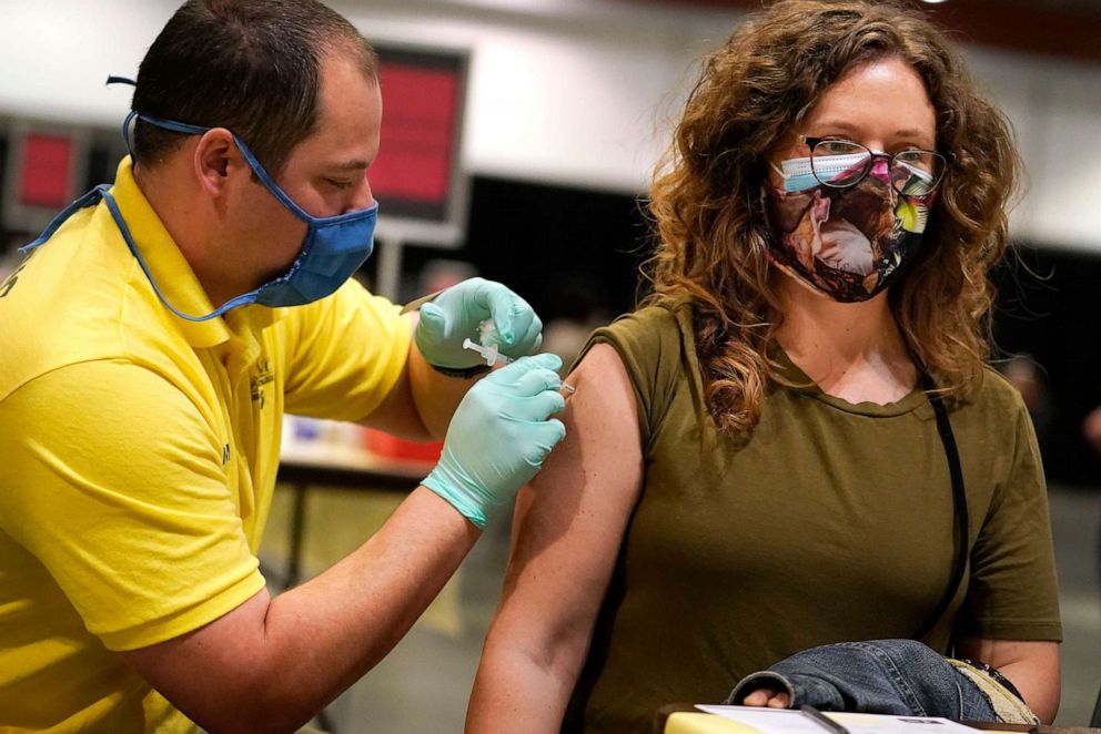 PHOTO: Nicole Torres, right, receives Pfizer's COVID-19 vaccine at the Music City Center convention facility, March 12, 2021, in Nashville, Tenn.