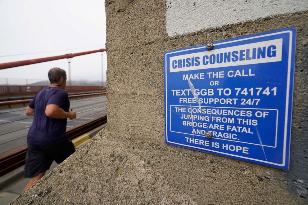 PHOTO: A man jogs past a sign about crisis counseling on the Golden Gate Bridge in San Francisco, Aug. 3, 2021.