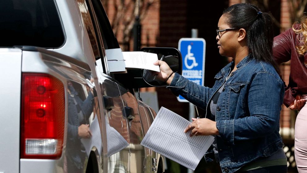PHOTO: Amour Fowler, a Jackson, Miss., precinct poll manager delivers a ballot to a curbside voter in Jackson, Miss., March 10, 2020.