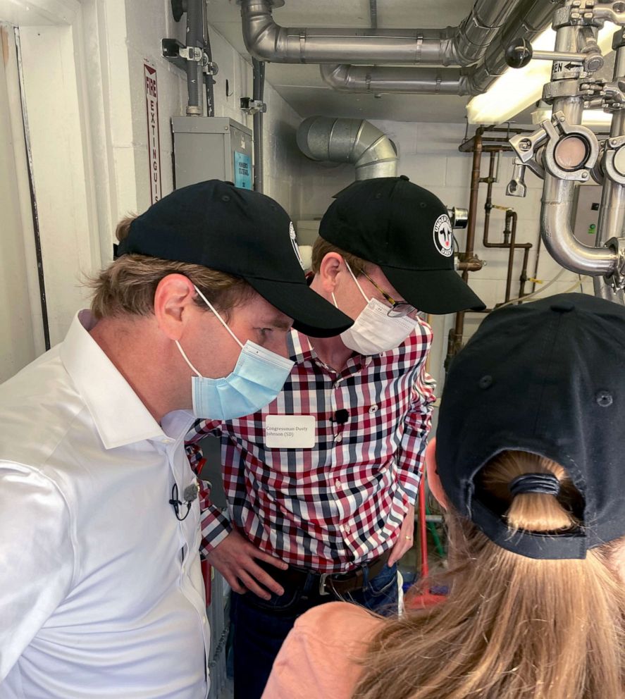 PHOTO: Rep. Dean Phillips of Minnesota, left, and Rep. Dusty Johnson of South Dakota, right, receive instructions for how to pour and serve fresh milk at the Minnesota State Fair.