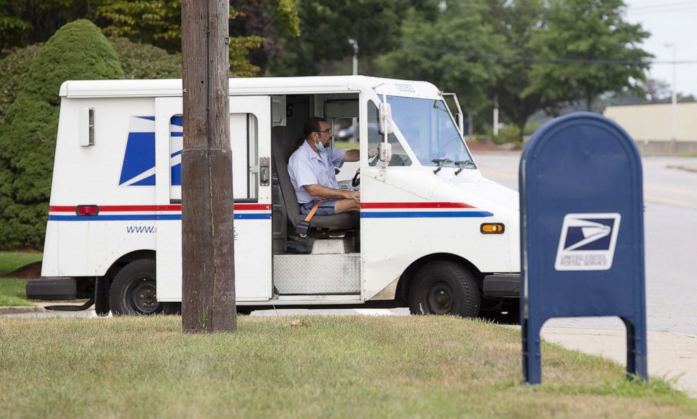 PHOTO: A United States Postal Service mail carrier drives his vehicle past a collection box in Woburn, Mass., August 17, 2020. 