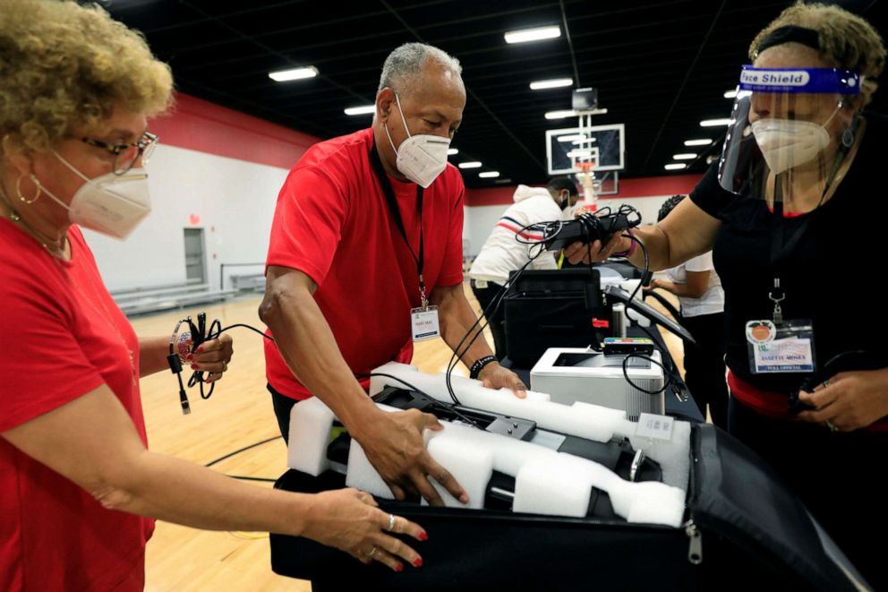 PHOTO: Poll workers Annette Reynolds, Perry Neal and Annette Moses pack up voting machines at an early voting location in Dekalb County for the upcoming presidential elections in Chamblee, Ga., Oct. 9, 2020.