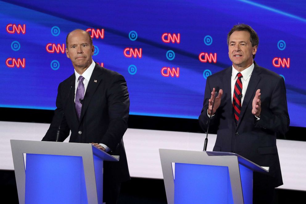 PHOTO: Democratic presidential candidate Montana Gov. Steve Bullock, right, speaks while former Maryland congressman John Delaney listens, during the Democratic Presidential Debate at the Fox Theatre, July 30, 2019, in Detroit.