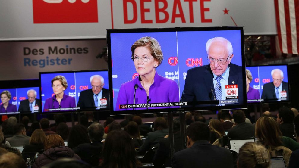 PHOTO: Sen. Elizabeth Warren and Sen. Bernie Sanders are seen on television monitors in the press room at the seventh Democratic 2020 presidential debate at Drake University in Des Moines, Iowa, Jan. 14, 2020.