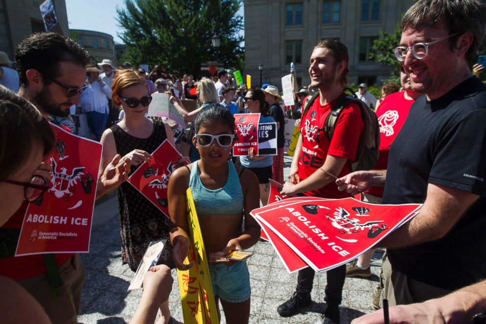 PHOTO: Bill Harshbarger, secretary of the Iowa City chapter of Democratic Socialists of America, hands out signs during a Families Belong Together rally in Iowa City, June 30, 2018.