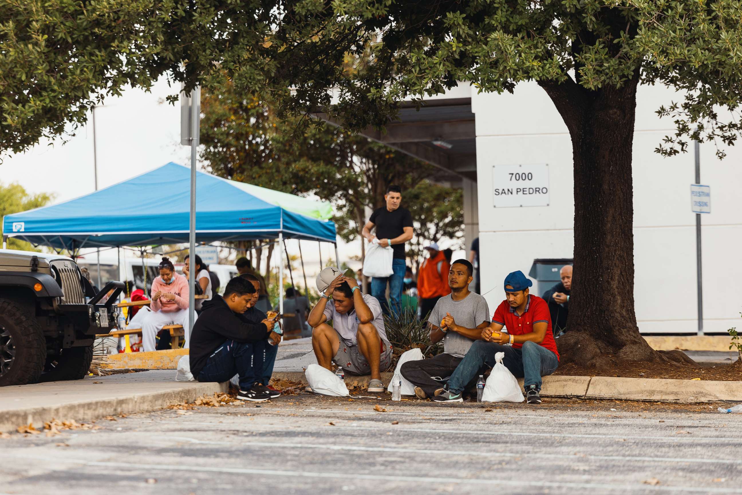 PHOTO: Groups of migrants sit outside the Migrant Resource Center in San Antonio, Texas, Sept. 19, 2022.