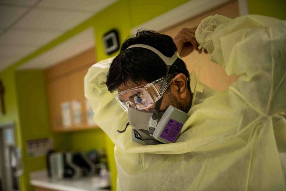 PHOTO: Dr. Abhishek Patel puts on personal protective equipment before entering the room of one of his youngest patients in the pediatric intensive care unit of the Children's Hospital of San Antonio in Texas, Aug. 10, 2021.