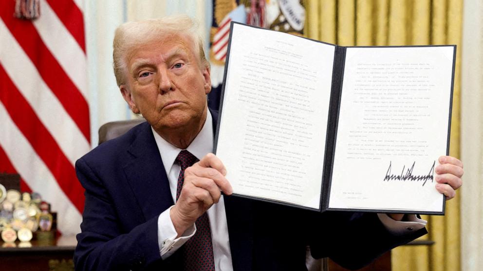 PHOTO: President Donald Trump holds a signed executive order on cryptocurrencies, in the Oval Office of the White House, in Washington, U.S., January 23, 2025.