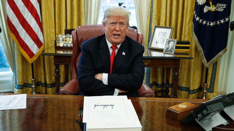 President Donald Trump speaks with reporters after signing the tax bill and continuing resolution to fund the government, in the Oval Office of the White House, Dec. 22, 2017, in Washington. 