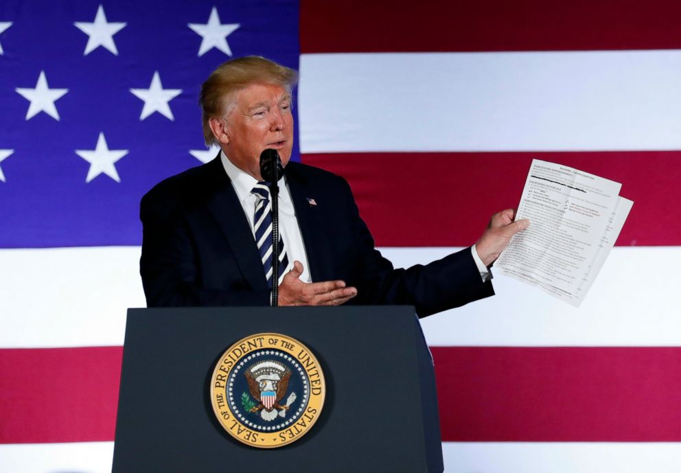 In this Aug. 31, 2018, photo, President Donald Trump holds up a list of his administrations accomplishments while speaking at a Republican fundraiser at the Carmel Country Club in in Charlotte, N.C.