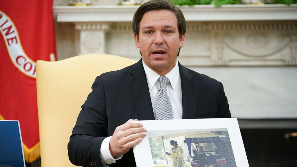 PHOTO: Florida Governor Ron DeSantis holds up a photo during a meeting with President Donald Trump in the Oval Office of the White House in Washington, April 28, 2020.
