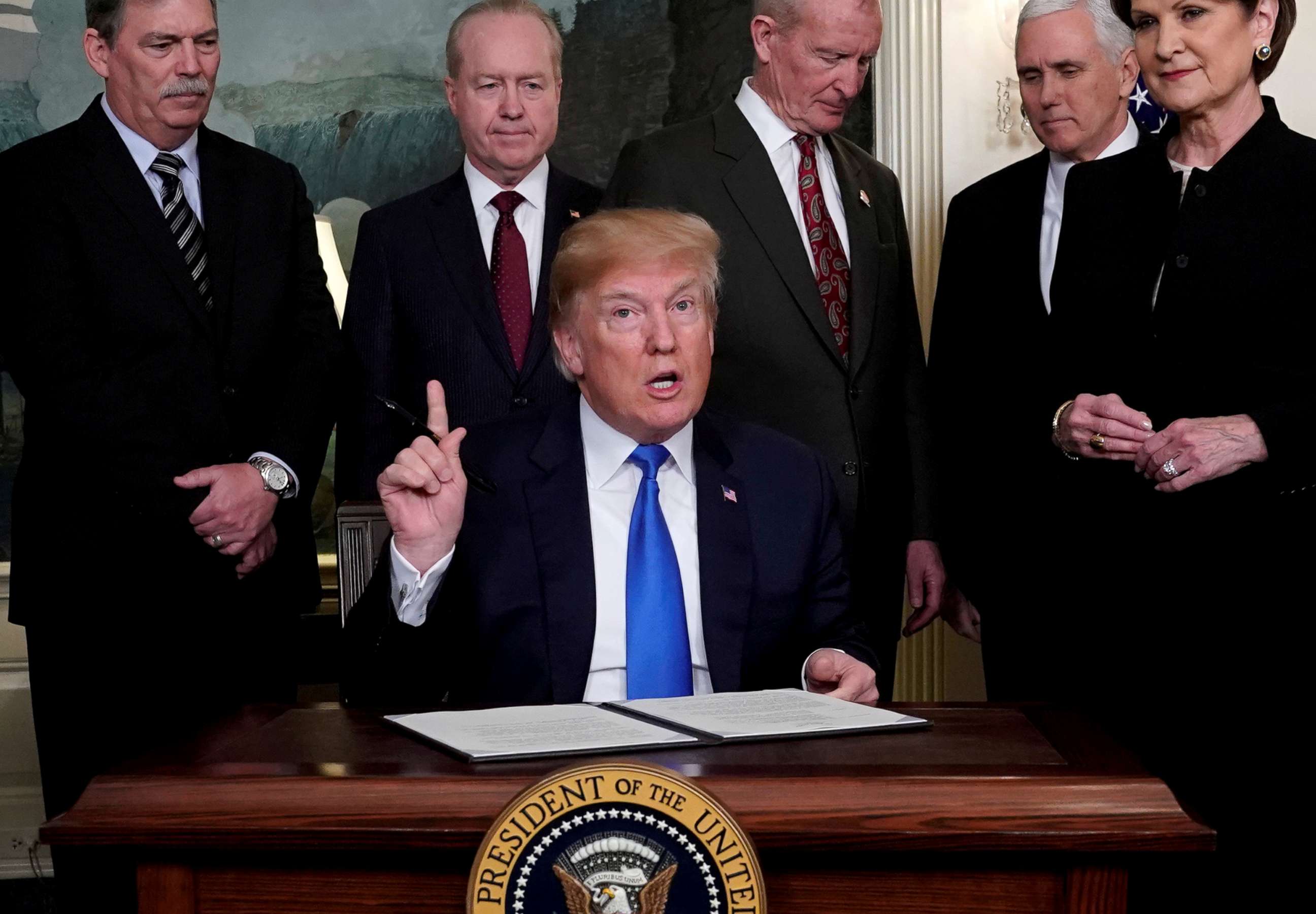 PHOTO: President Donald Trump, surrounded by business leaders and administration officials, prepares to sign a memorandum on intellectual property tariffs on high-tech goods from China, at the White House in Washington, March 22, 2018.