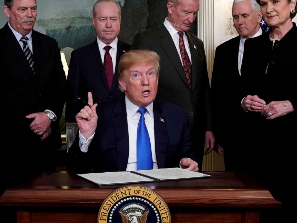 PHOTO: President Donald Trump, surrounded by business leaders and administration officials, prepares to sign a memorandum on intellectual property tariffs on high-tech goods from China, at the White House in Washington, March 22, 2018.