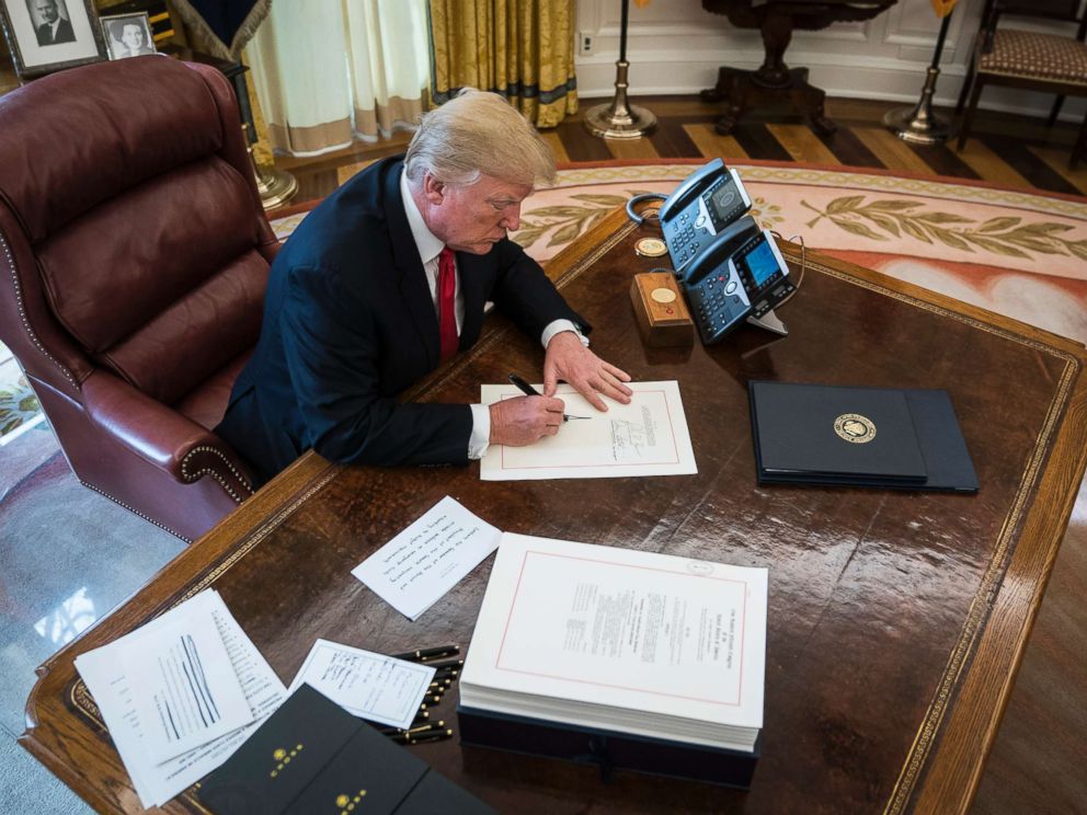 PHOTO: President Donald Trump signs the Tax Cut and Reform Bill, a $1.5 trillion tax overhaul package, into law in the Oval Office at the White House in Washington, D.C., Dec. 22, 2017.