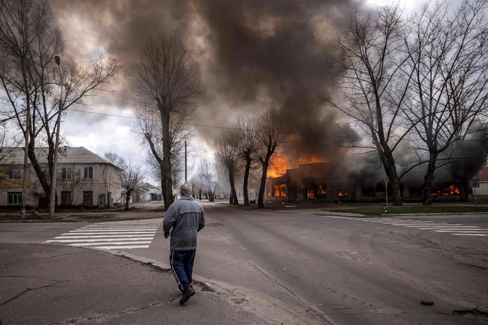PHOTO: A man walks on a pavement as a house is burning following a shelling Severodonetsk, Donbass region, on April 6, 2022.
