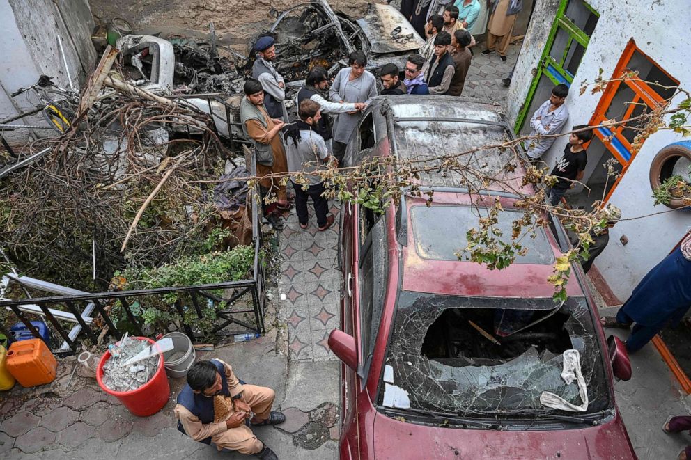 PHOTO: Afghan residents gather next to a damaged vehicle a day after a U.S. drone airstrike in Kabul on Aug. 30, 2021. 