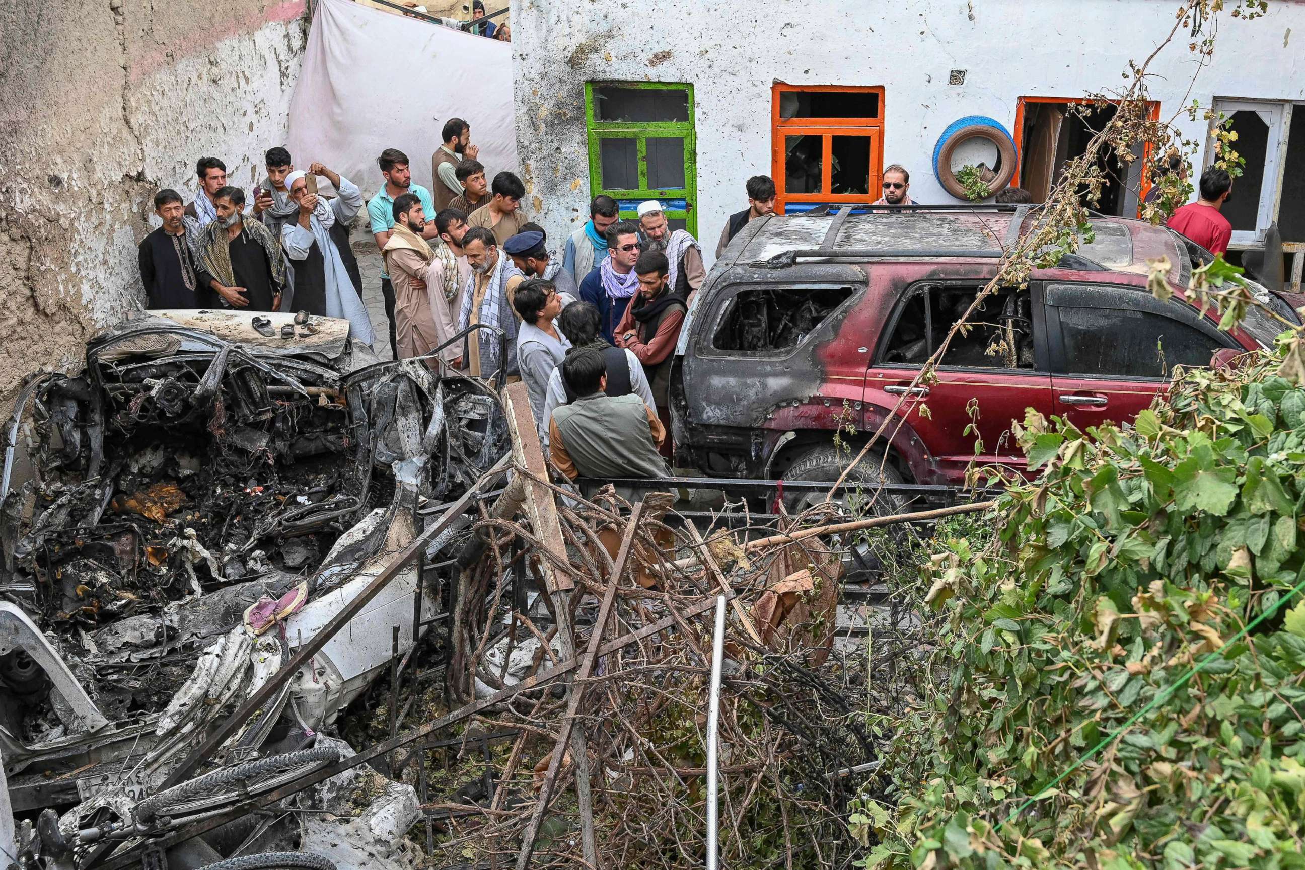 PHOTO: Afghan residents gather next to a damaged vehicle a day after a U.S. drone airstrike in Kabul on Aug. 30, 2021. 