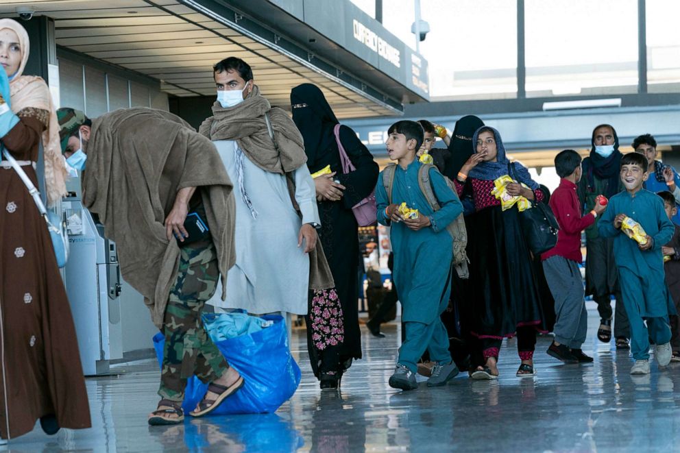 PHOTO: People evacuated from Kabul, Afghanistan, walk through the terminal before boarding a bus after they arrived at Washington Dulles International Airport, in Chantilly, Va., on Sept. 2, 2021.