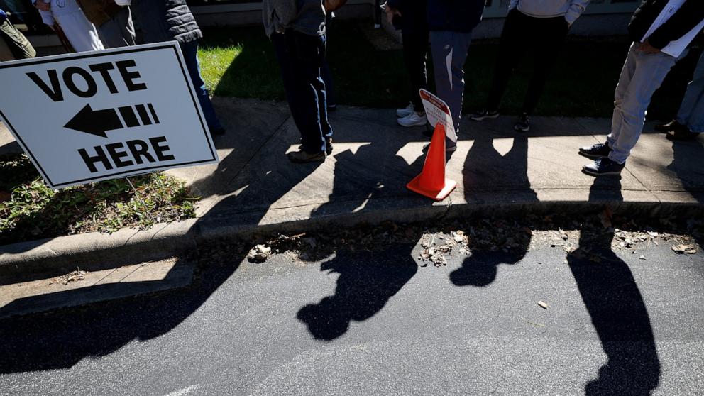 PHOTO: Residents cast shadows as they wait in line to enter a polling site on the first day of early in-person voting in a region still severely impacted by Hurricane Helene, in Asheville, North Carolina, October 17, 2024.