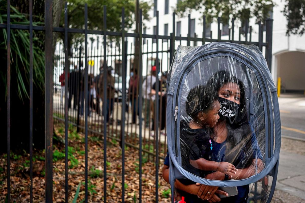 PHOTO: Dana Clark, and her son 18-month-old Mason, wait in line at City Hall as early voting begins for the upcoming presidential election in New Orleans, Oct. 16, 2020.