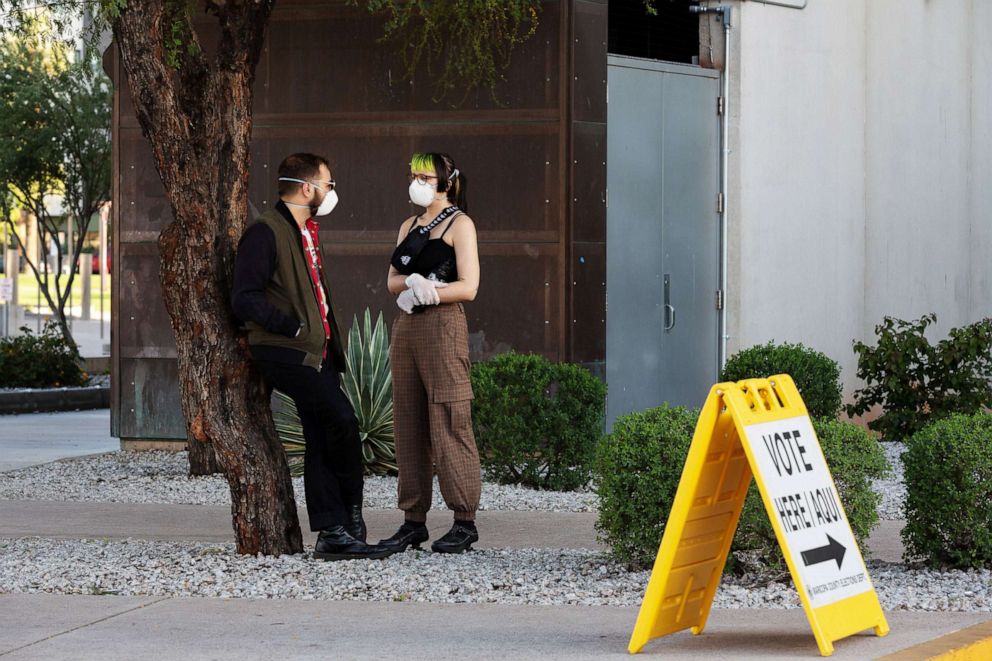 PHOTO: Gage Olesen, 26, (left) and Merz, 22, stand outside a polling station after casting their ballots, while wearing masks amid coronavirus concerns, at the Burton Barr Library in Phoenix, March 17, 2020. 