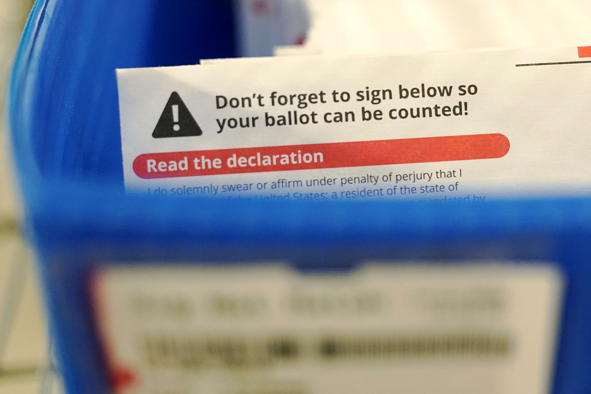 PHOTO: A reminder that voters need to sign their ballots sits in a box of ballots awaiting signature verification at the King County election headquarters in Renton, Wash., Oct. 23, 2020