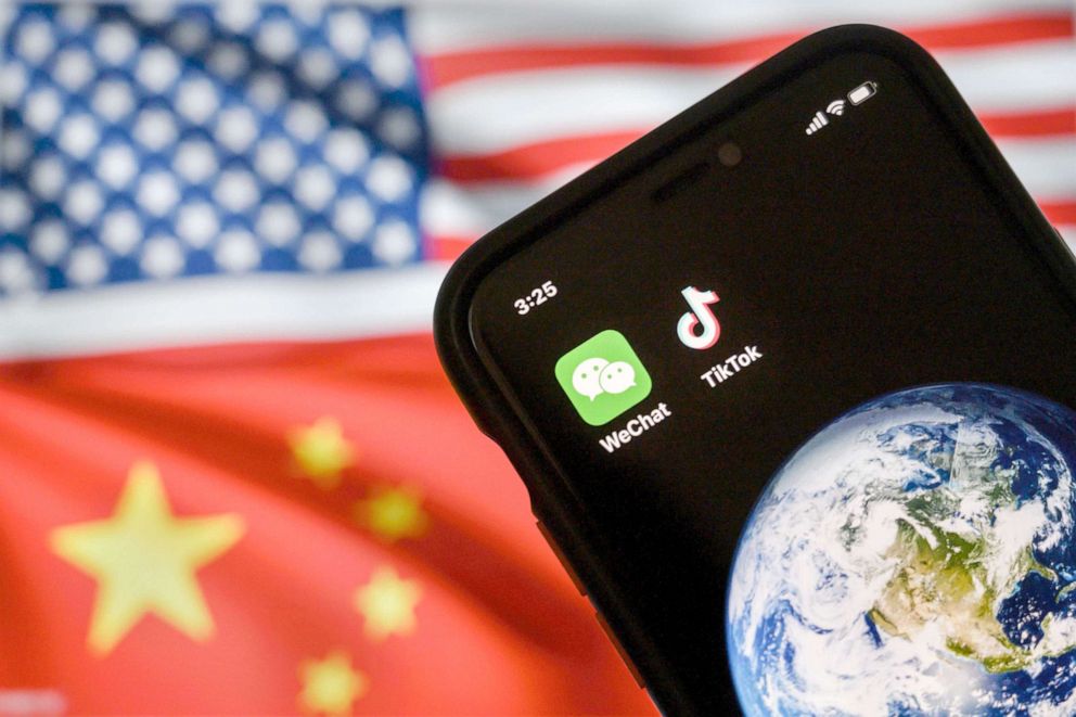 PHOTO: A mobile phone displays the logos for Chinese apps WeChat and TikTok in front of a monitor showing the flags of the United States and China on an internet page in Beijing, Sept. 22, 2020.