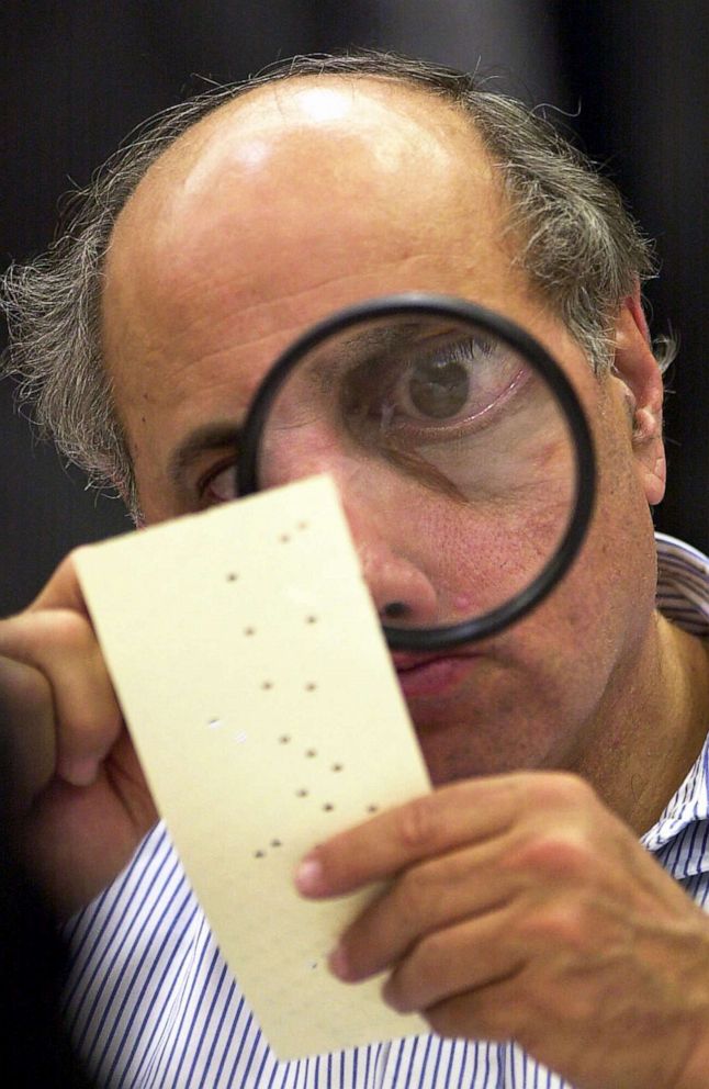 PHOTO: Broward County canvassing board member Judge Robert Rosenberg uses a magnifying glass to examine a disputed ballot at the Broward County Courthouse in Fort Lauderdale, Fla., Nov. 24, 2000.