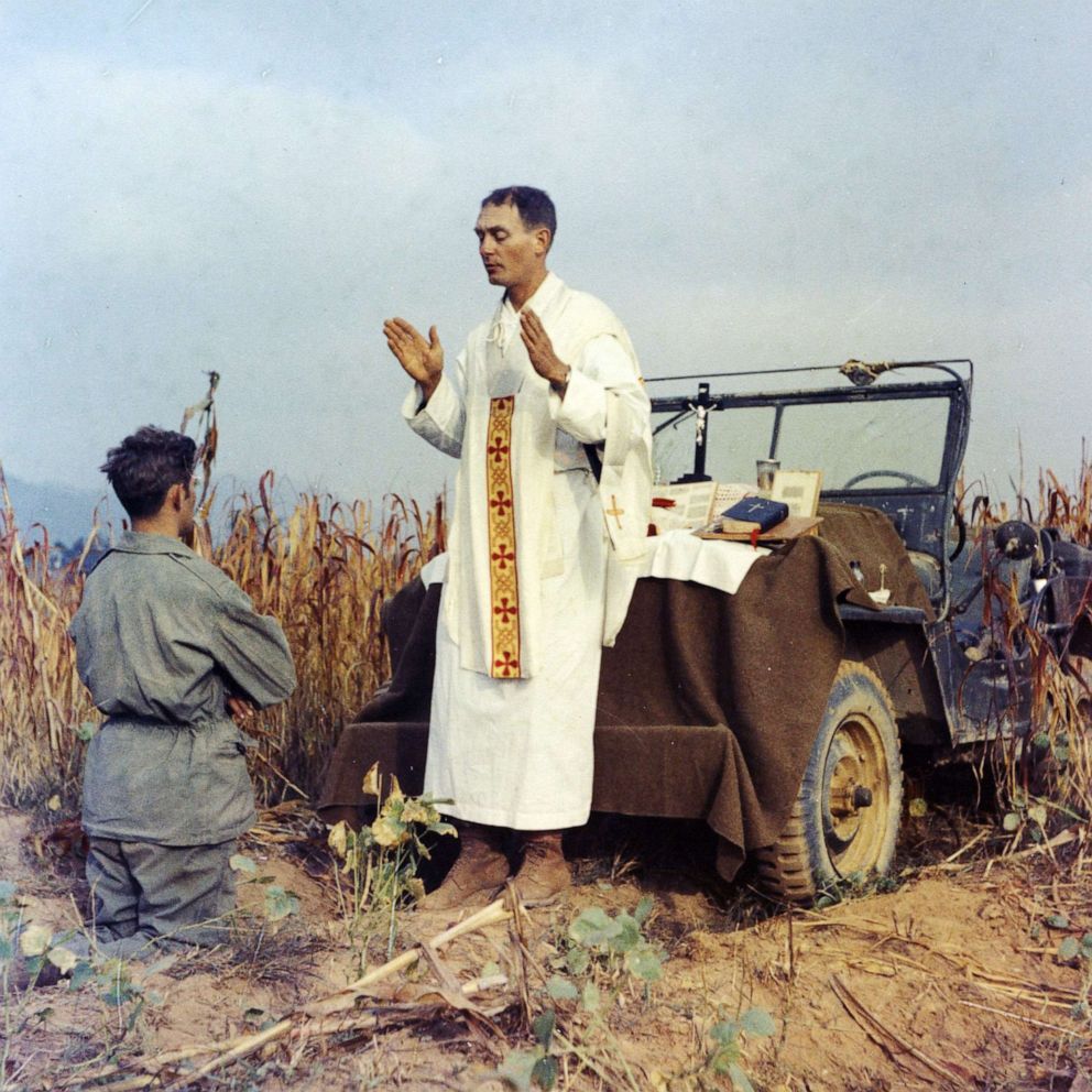PHOTO: Father Emil Kapaun celebrates Mass using the hood of his jeep as an altar, as his assistant, Patrick J. Schuler, kneels in prayer in Korea on Oct. 7, 1950.
