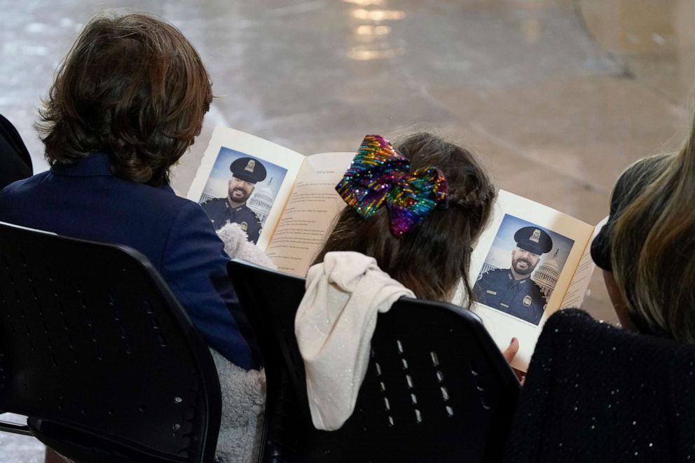 PHOTO: Logan Evans (L) and Abigail Evans, children of late U.S. Capitol Police officer William Evans, look at the program with a photo of their father as he lies in honor in the U.S. Capitol rotunda, April 13, 2021 in Washington, DC.