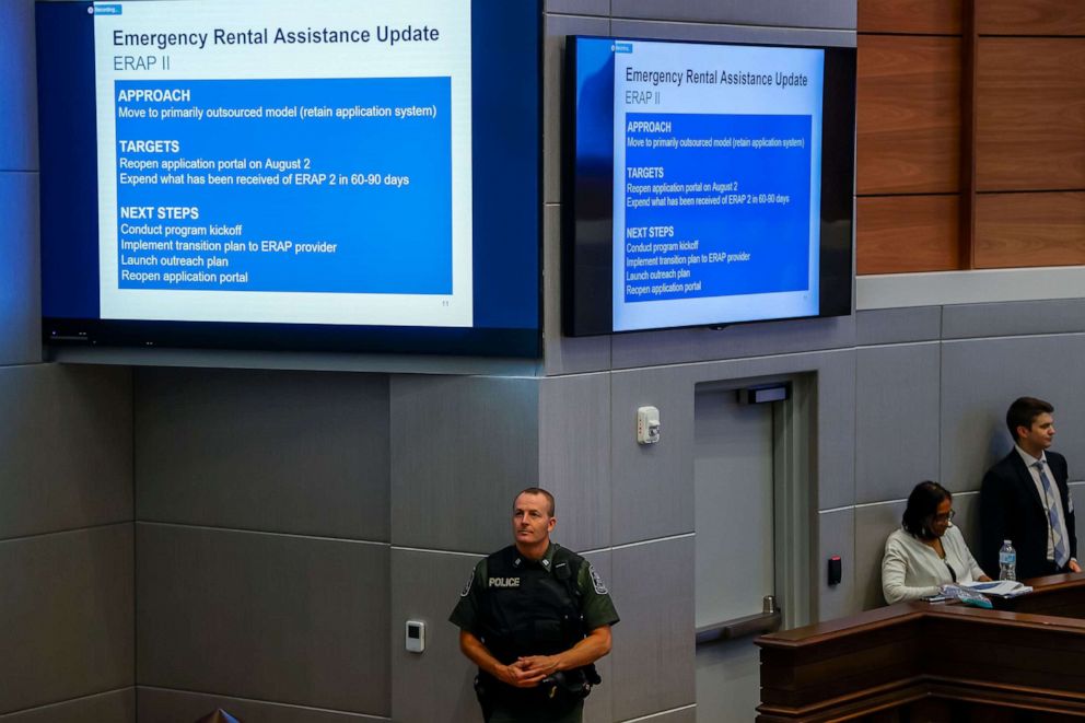 PHOTO: A Fulton County Police officer stands below information to assist renters overdue or financially stressed on their housing rental payments in Atlanta, Aug. 2, 2021. 