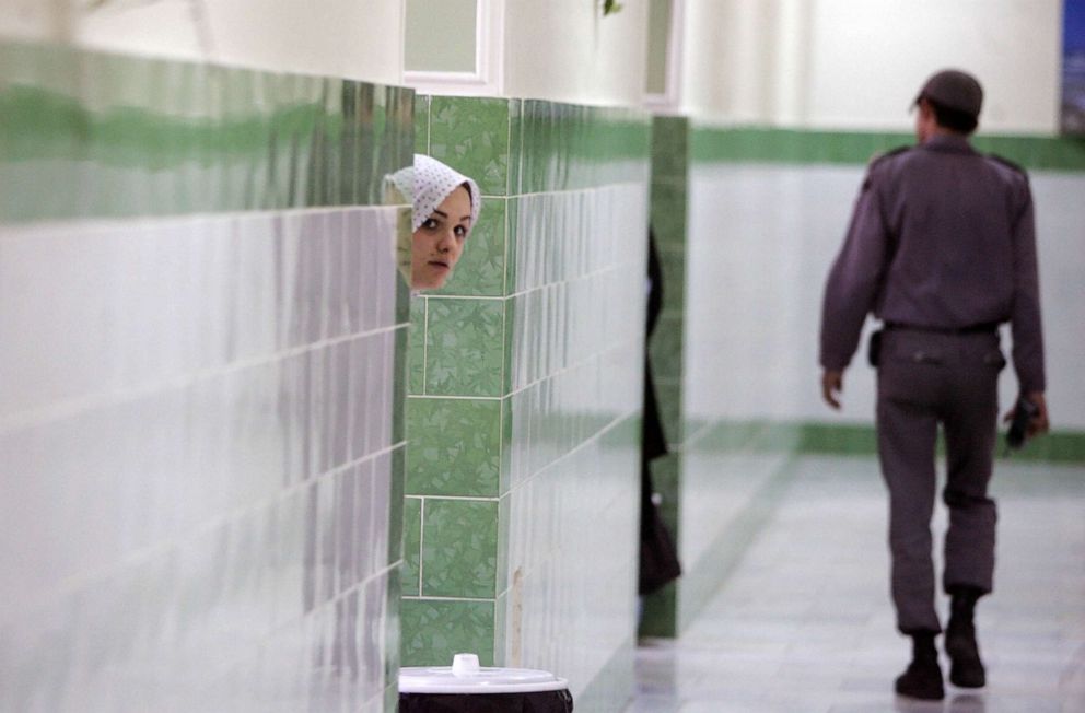 PHOTO: FILE - An Iranian prisoner peers from behind a wall as a guard walks by in the women's section of the notorious Evin Prison, north of Tehran, June 13, 2006.