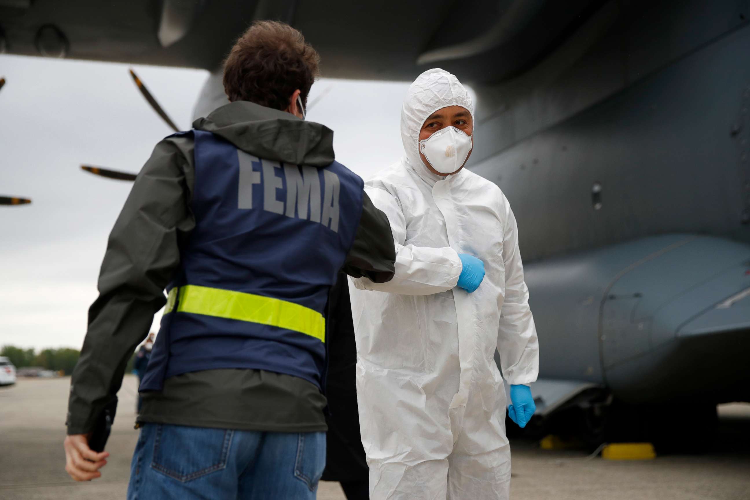 PHOTO: A Turkish military flight crew member bumps elbows with a FEMA worker as crews unload a donation of medical supplies from Turkey, April 28, 2020, at Andrews Air Force Base, Md.