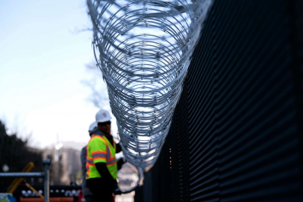 PHOTO: Workers install barbed wire on security fencing surrounding the U.S. Capitol on Jan. 14, 2021 in Washington, D.C.