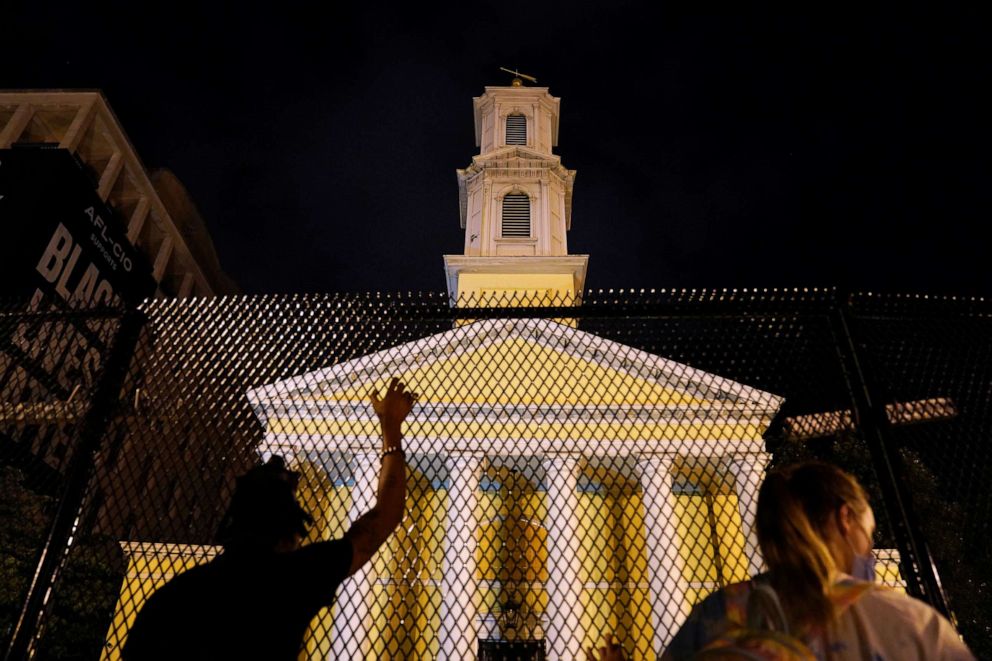 PHOTO: People look through a fence erected around St John's Church, which has been barricaded, during racial inequality protests near the White House in Washington, D.C., early June 24, 2020.