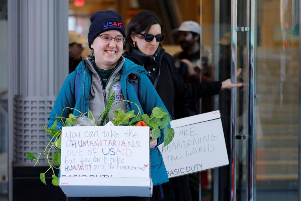 PHOTO: Recently fired U.S. Agency for International Development (USAID) staff carry boxes with a message as they leave work outside USAID offices in Washington, D.C., Feb. 21, 2025.   
