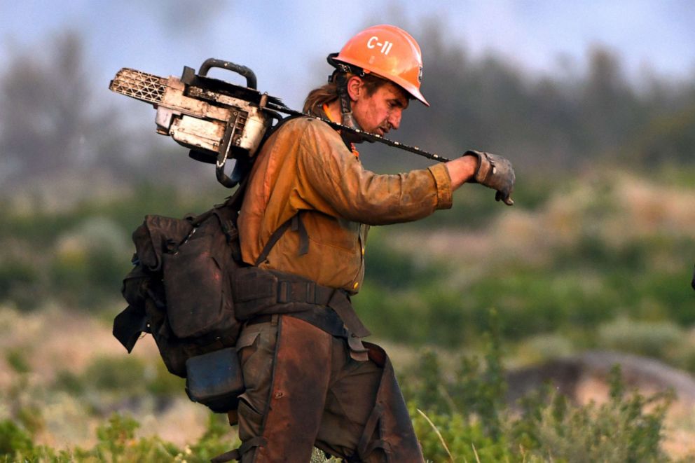 PHOTO: A member of the U.S. Forest Service's Trinity Hotshots firefighting crew carries a chain saw while hiking out of the burn zone, June 28, 2021, at the Lava Fire north of Weed, Calif.