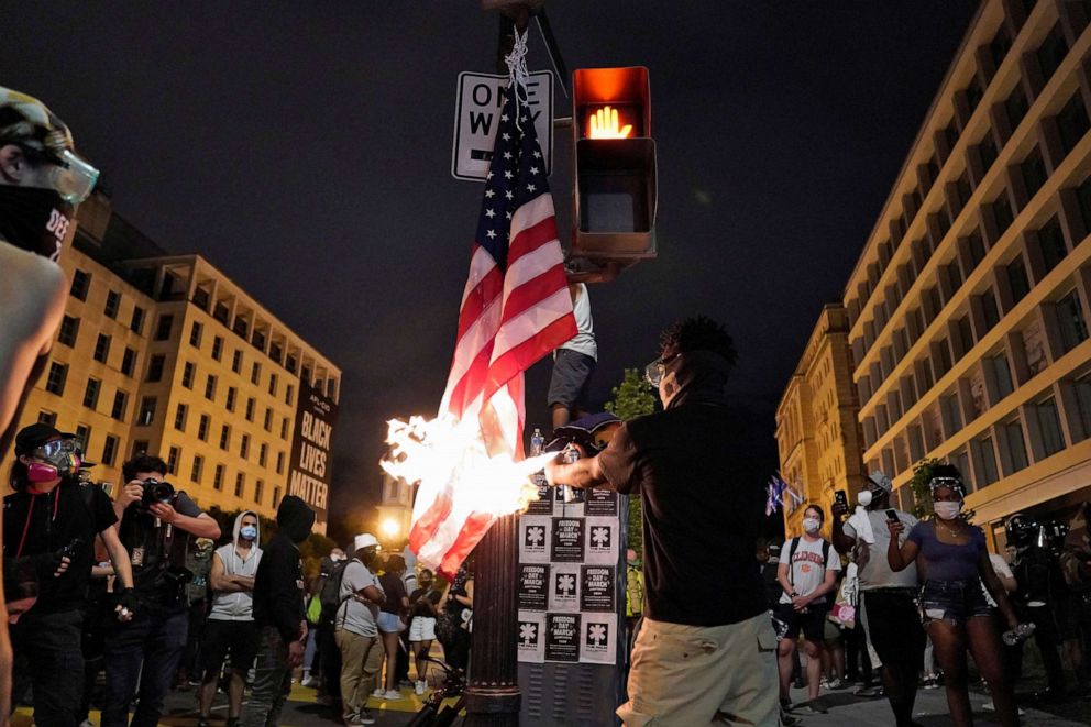 PHOTO: A demonstrator burns a U.S. flag during racial inequality protests near the White House in Washington, D.C., June 23, 2020.