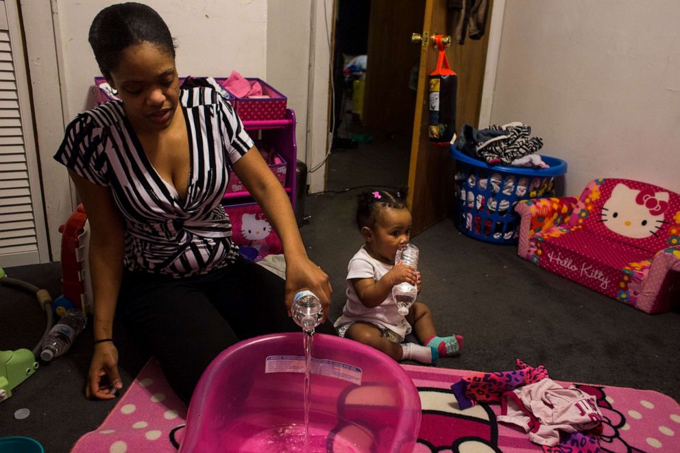 PHOTO: Brittny Giles pours bottled water in a tub as she prepares to give her 9-month-old daughter, Joel, a bath at her home in Flint, Mich., Feb. 4, 2016. Giles used five bottles of water for bathing and a space heater to keep Joel warm.