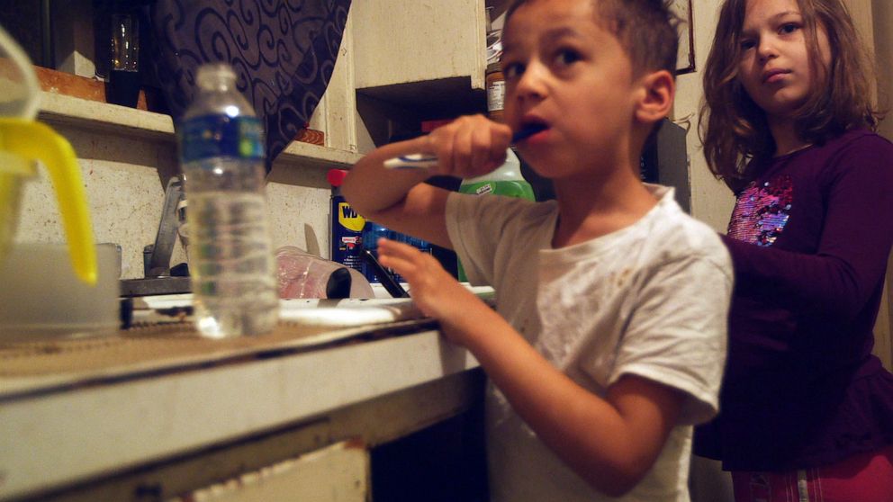 PHOTO: Gabriel and Nala Uherek brush their teeth using bottled water in their family's home in Flint, Mich.