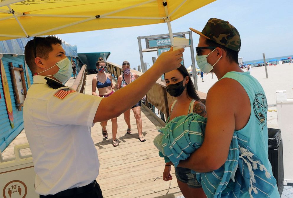 PHOTO: People wear face masks and undergo mandatory temperature checks before entering the pier on Independence Day, July 4, 2020, in Cocoa Beach, Florida.
