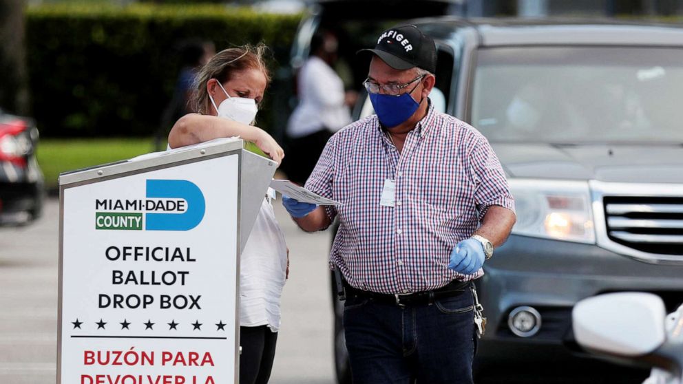 PHOTO: Poll workers at the Miami-Dade County Elections Department deposit voters' mail in ballots into an official ballot drop box on primary election day in Doral, Fla., Aug. 18, 2020.
