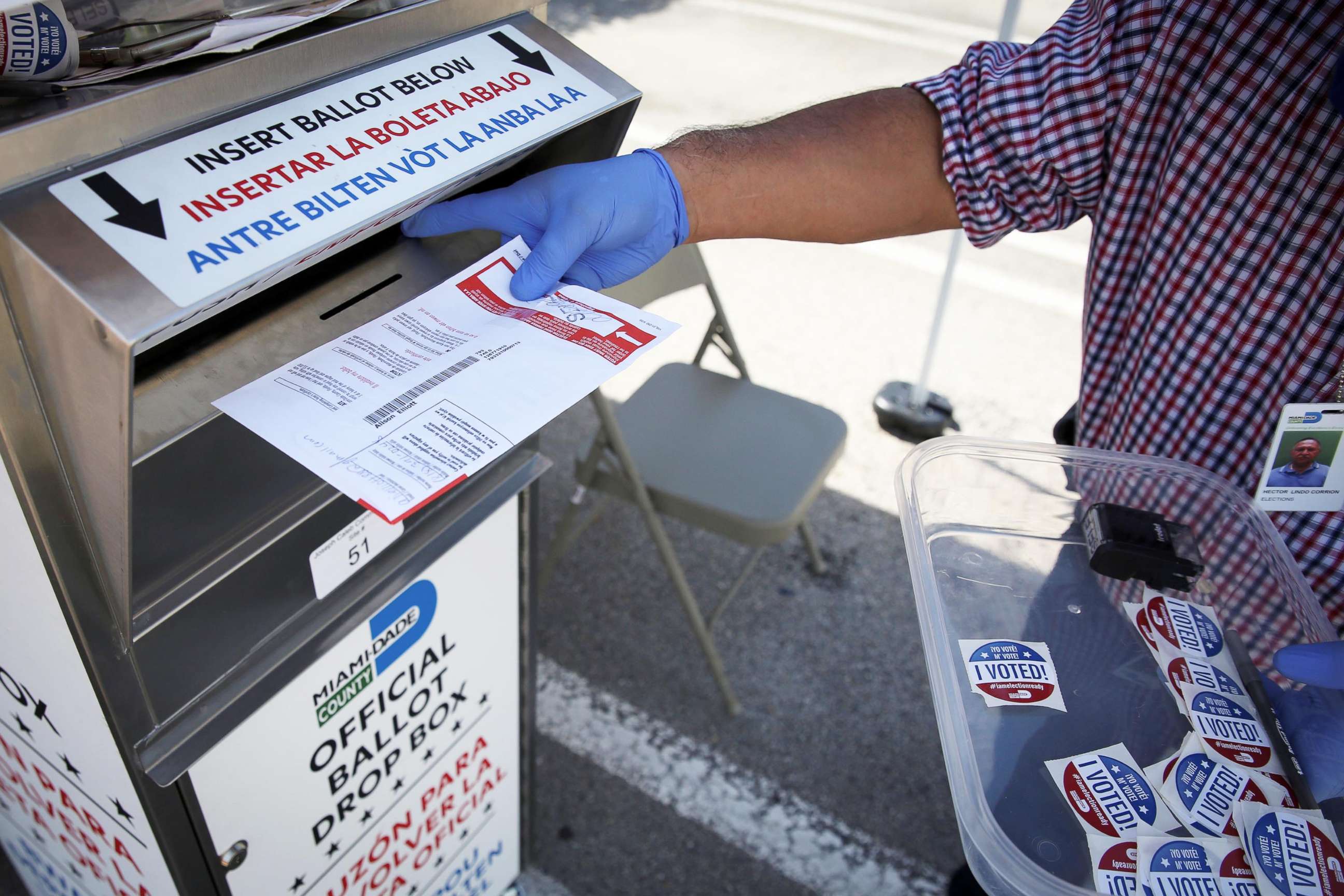 PHOTO: A poll worker casts a mail-in ballot for a voter at a drive-thru polling station during the primary election amid the COVID-19 outbreak in Miami, Aug. 18, 2020.
