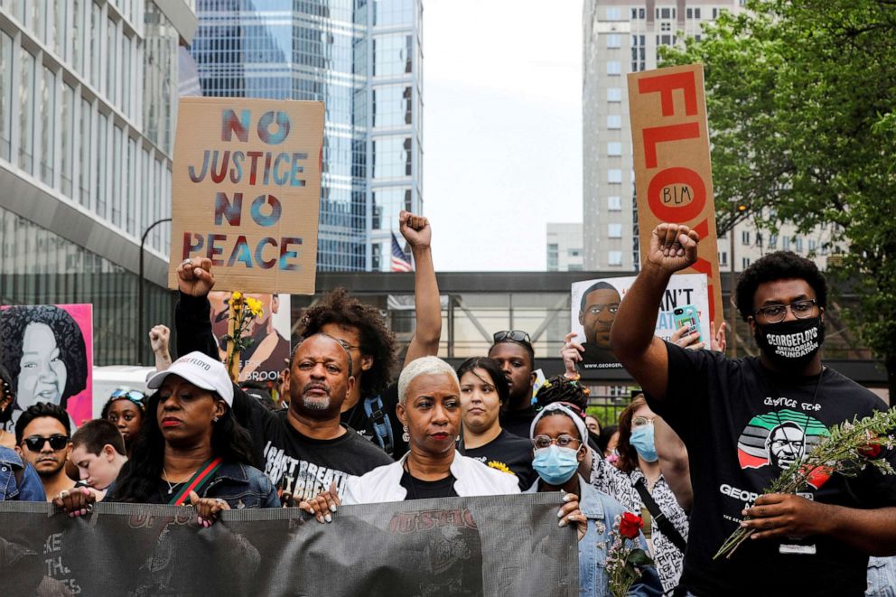 PHOTO: George Floyd's cousin Shareeduh Tate and aunt Angela Harrelson hold a banner as they march with others during the "One Year, What's Changed?"outside the Hennepin County Government Center in Minneapolis, May 23, 2021. 