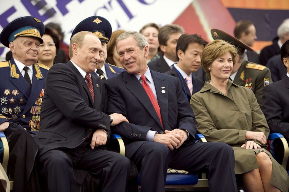 PHOTO: Former President George W. Bush, center, and Russian President Vladimir Putin, left, share a light moment as they sit with Laura Bush, right, and other heads of state during a  military parade in Red Square in Moscow, May 9, 2005.